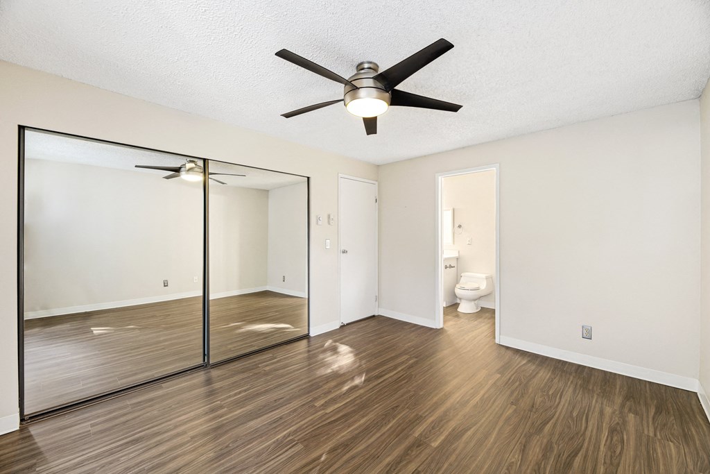 an empty living room with a ceiling fan and a mirror