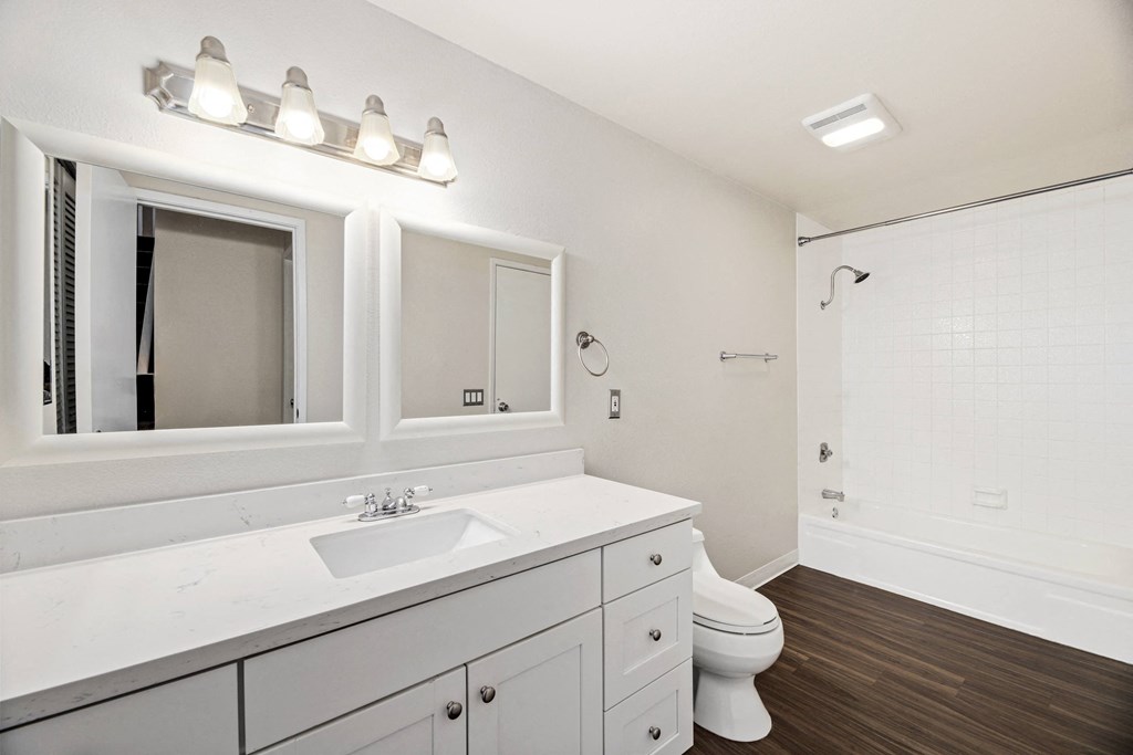 a white bathroom with a large mirror and a white toilet
