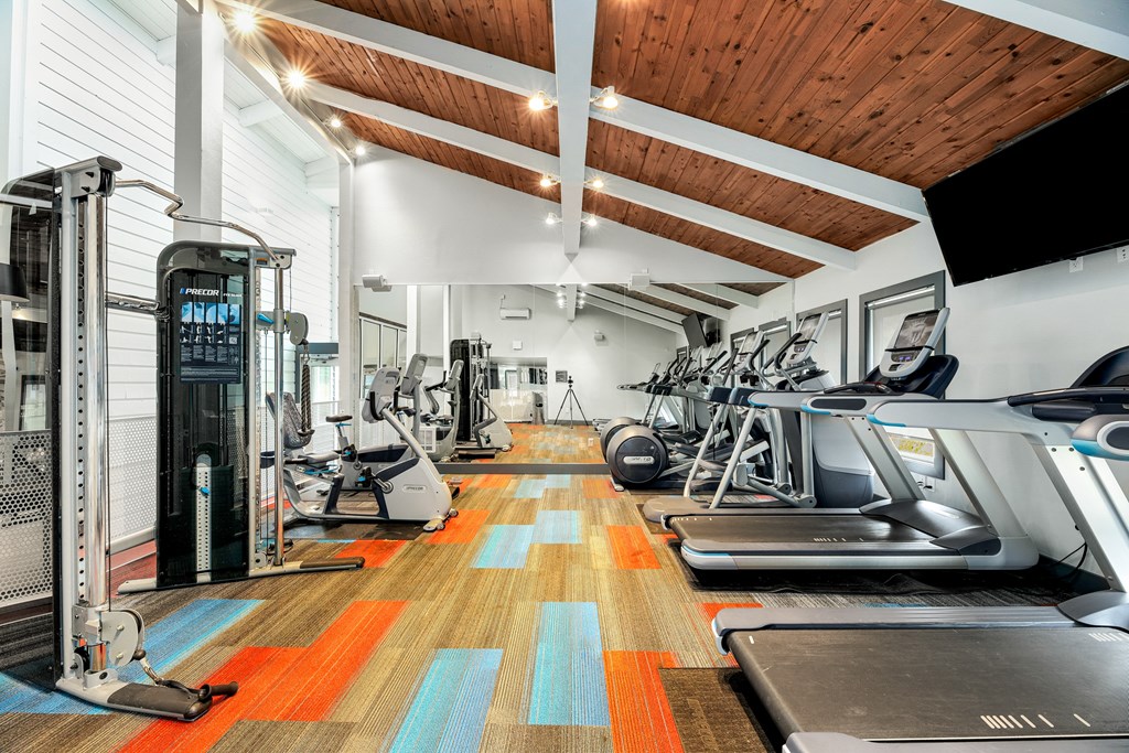 a gym with cardio machines and weights on the floor