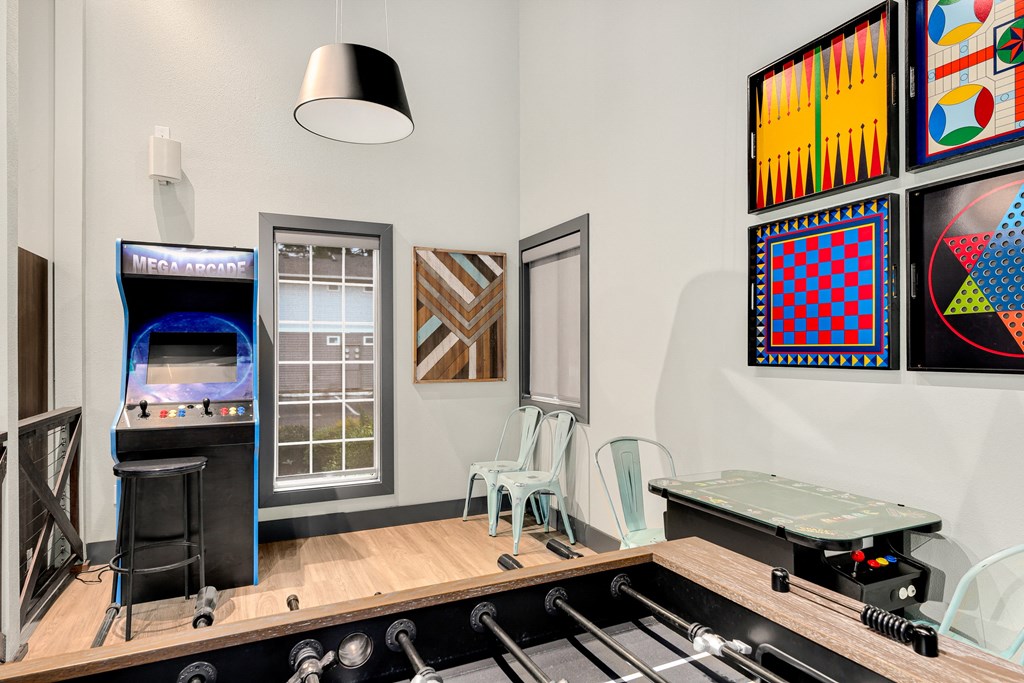 a room with a piano and a table with chairs and a video game on a