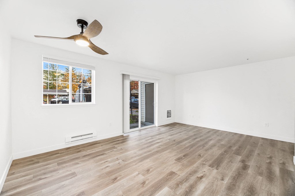 an empty living room with white walls and a ceiling fan