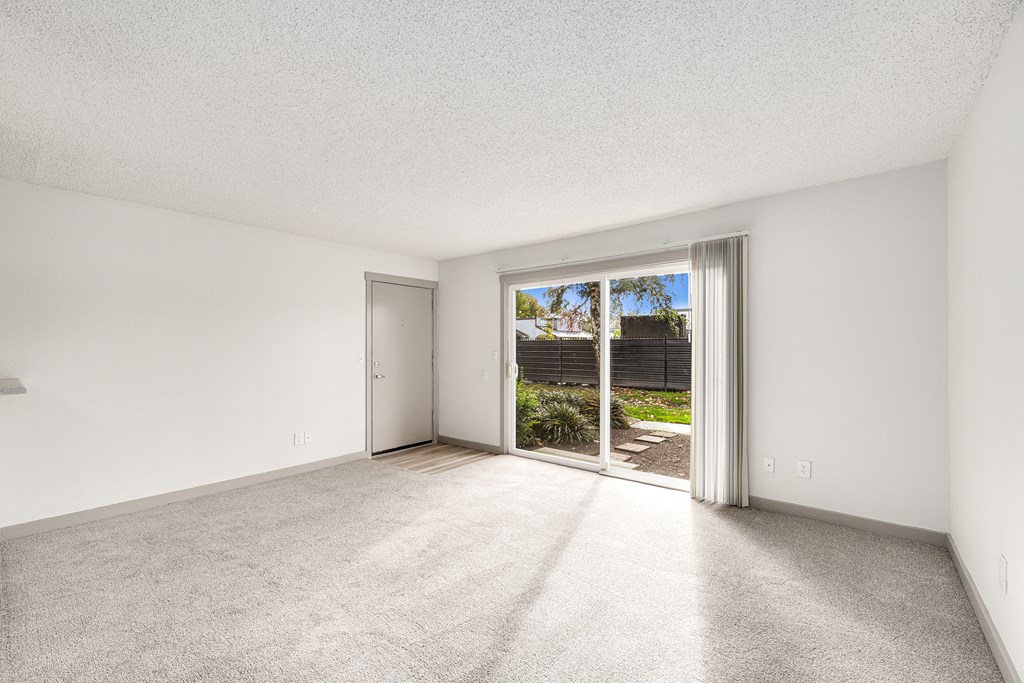 an empty living room with sliding glass doors to a patio