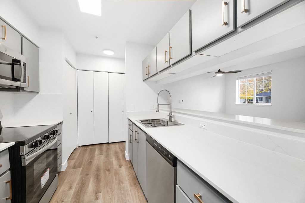 a white kitchen with stainless steel appliances and white counter tops