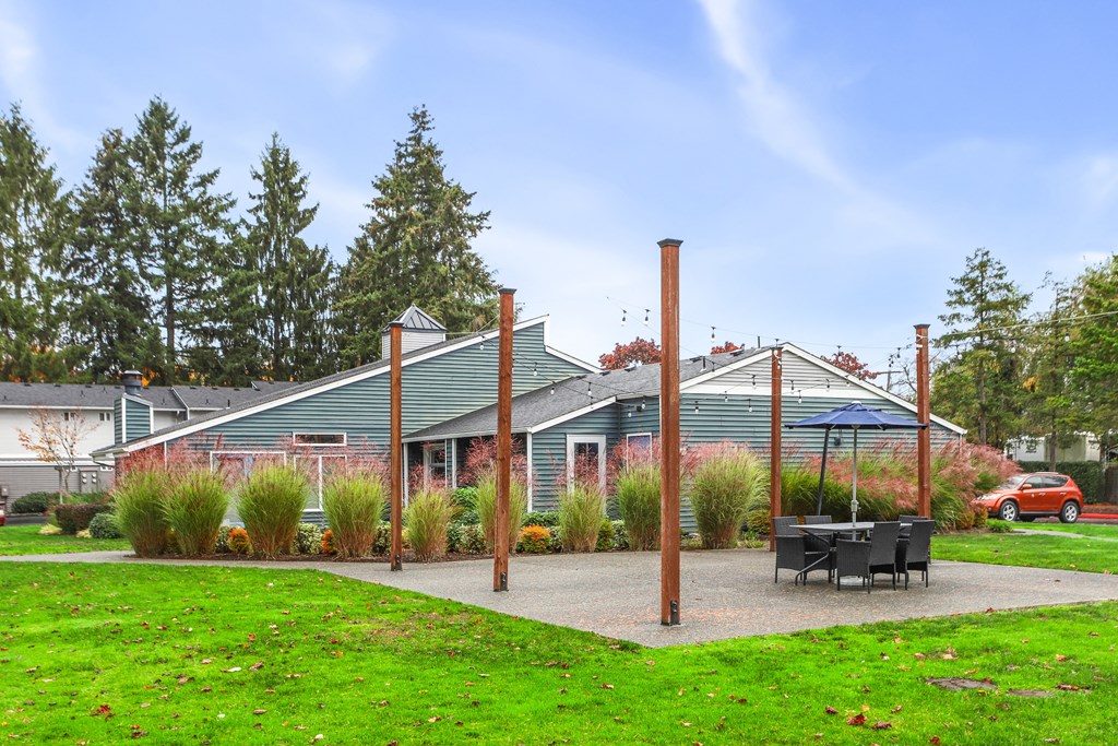 a patio with a table and chairs in front of a house