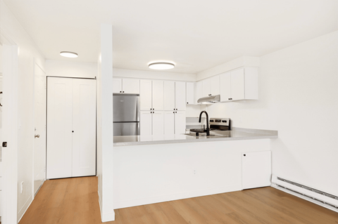 A kitchen with white cabinets and a wooden floor.