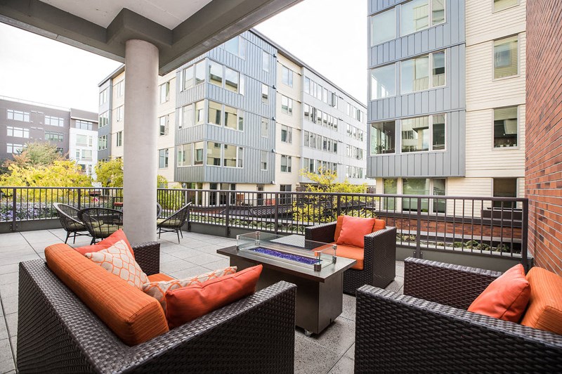 a patio with chairs and a table in front of apartment buildings