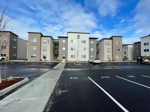 A parking lot in front of apartment buildings with a white car parked.