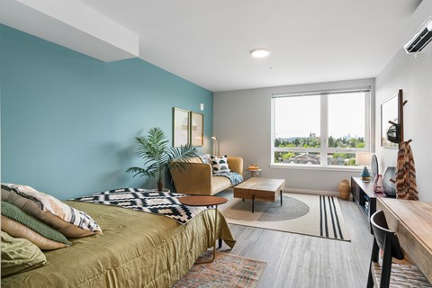 A bedroom with a bed, a couch, a chair, a table, and a window.