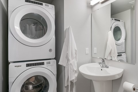 A white washing machine and dryer stacked on top of each other in a laundry room.