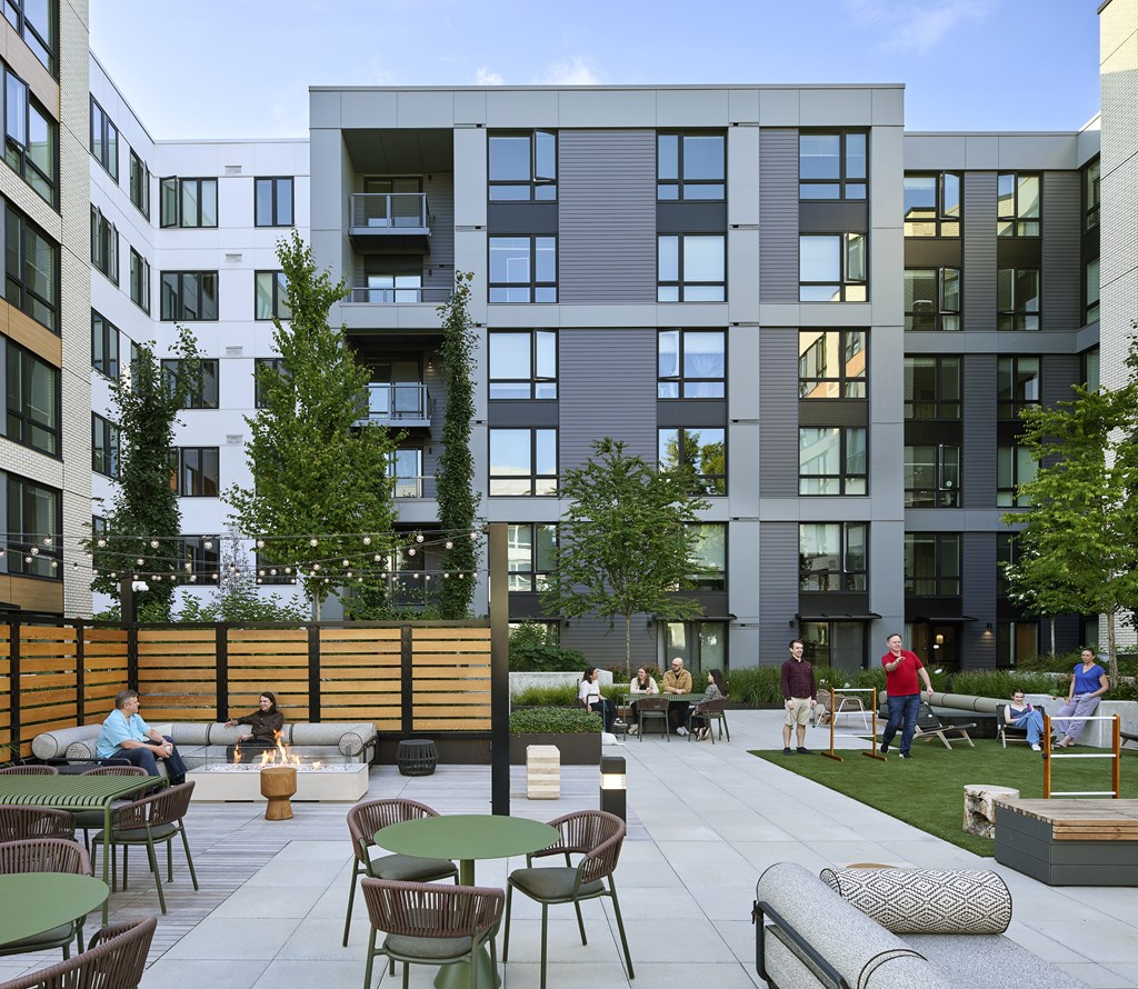A modern outdoor seating area with people sitting and standing around.