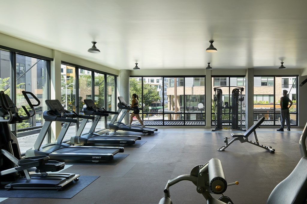 A gym with treadmills, elliptical machines, and a person working out.