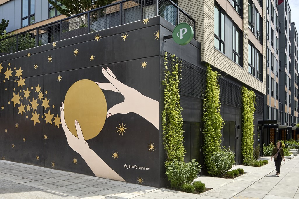 A mural of a hand holding a sun with stars around it.