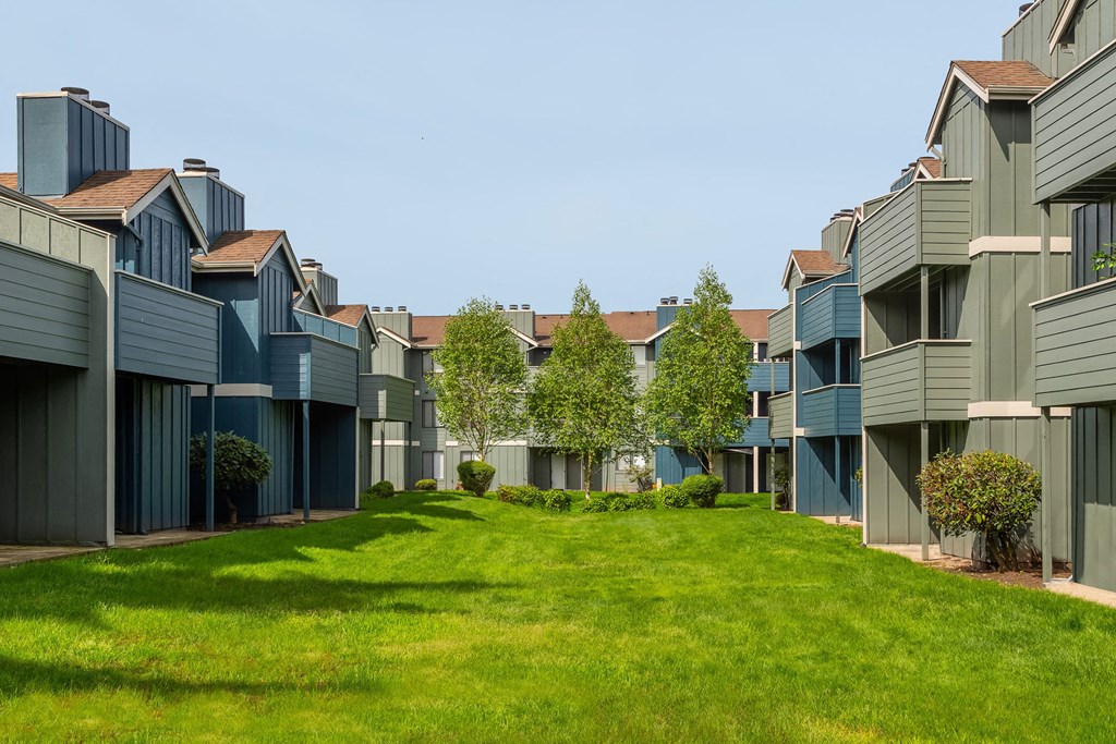 a row of apartments with green grass and trees