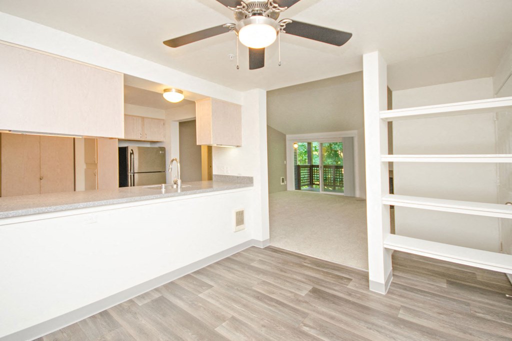 an empty living room and kitchen with a ceiling fan
