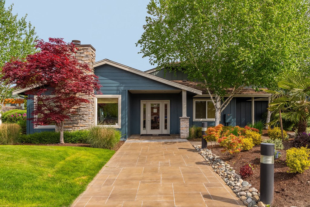 the front of a blue house with a walkway and trees