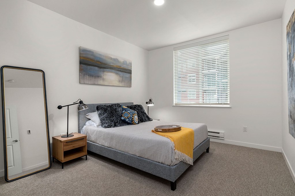 A bedroom with a bed, nightstand, and a painting on the wall.