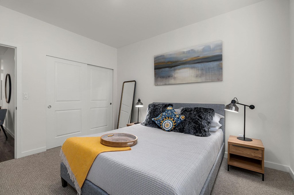 A bedroom with a bed, a lamp, and a painting on the wall.