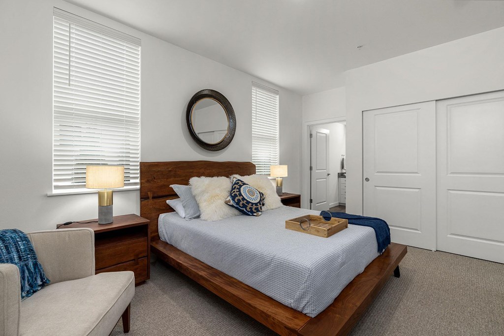 A bedroom with a bed, nightstand, and chair.