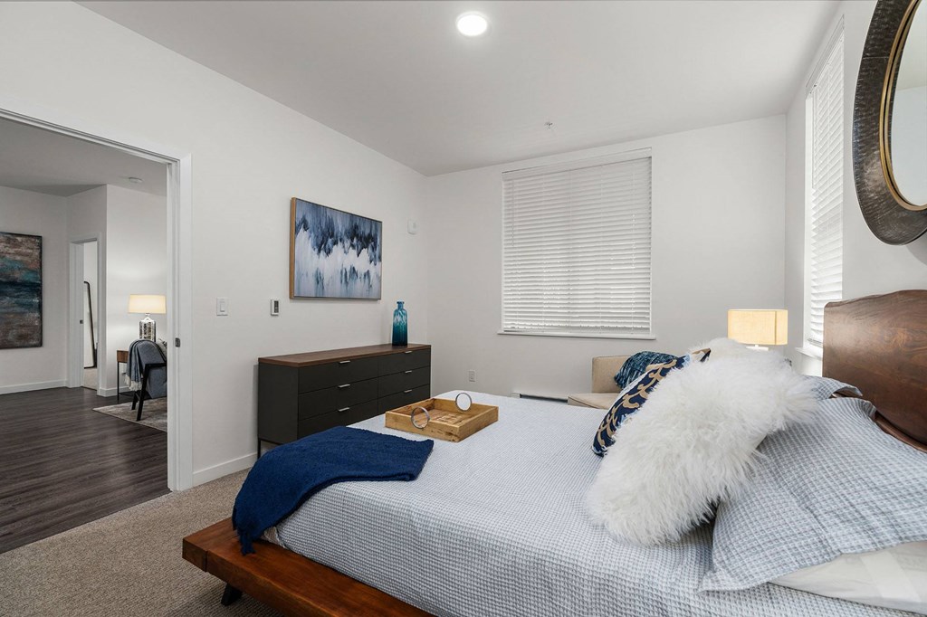 A bedroom with a bed, nightstand, and a painting on the wall.