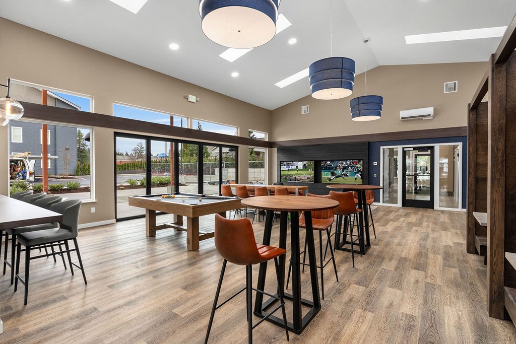 A room with a long table surrounded by chairs and a bar area.