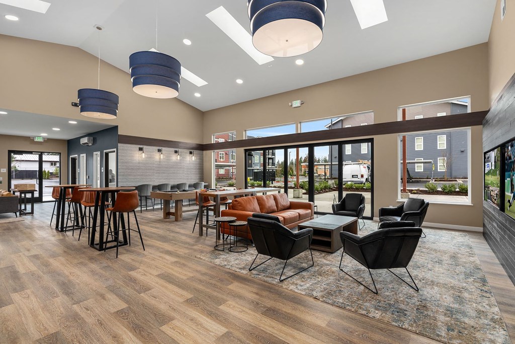 A spacious room with wooden floors and a variety of seating options.