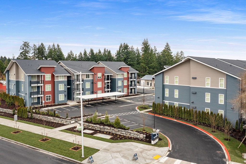 A view of apartment buildings with a parking lot in front.