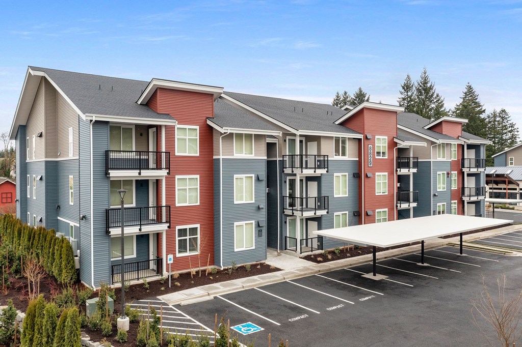 Apartment complex with a parking lot in front.