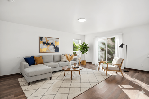 A living room with a grey couch and a painting on the wall.