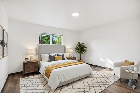 A bedroom with a large bed, a chair, and a potted plant.