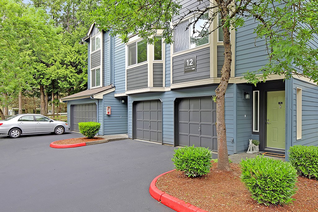 a street view of a blue house with a driveway and garage doors