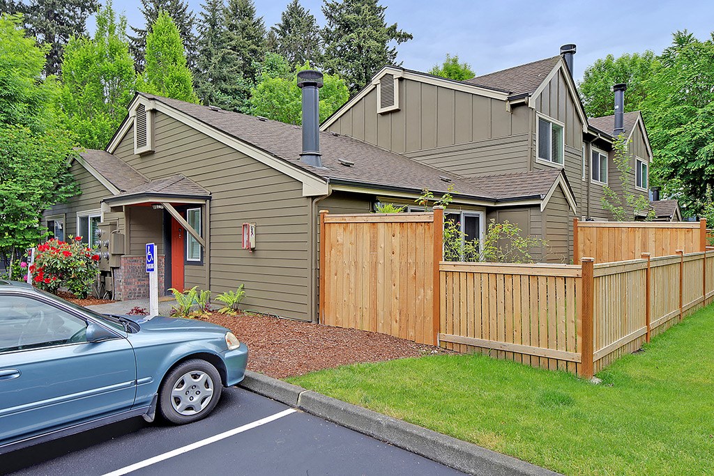a blue car parked in front of a wooden fence