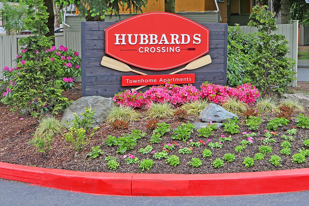 a sign for hubbards crossing in front of a flower garden