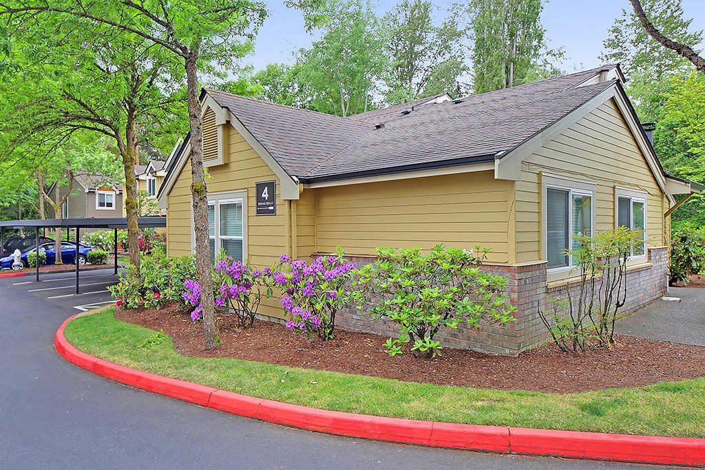 a small yellow house with flowers on the side of a street