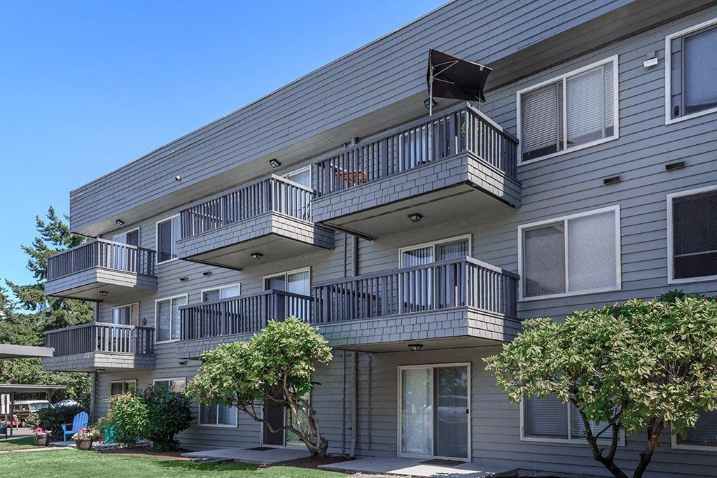 a gray apartment building with balconies and trees