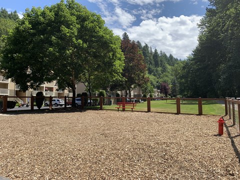 A playground with a red fire hydrant and a brown gravel ground.