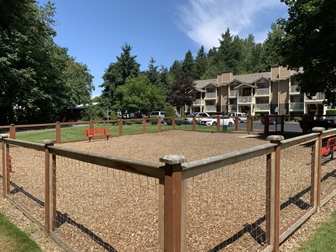 A playground with a wooden fence and a red slide.