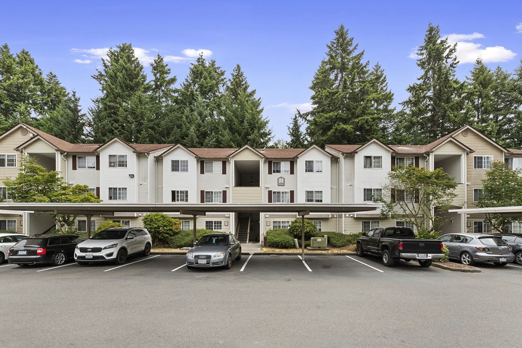 a parking lot in front of an apartment building with cars parked in front