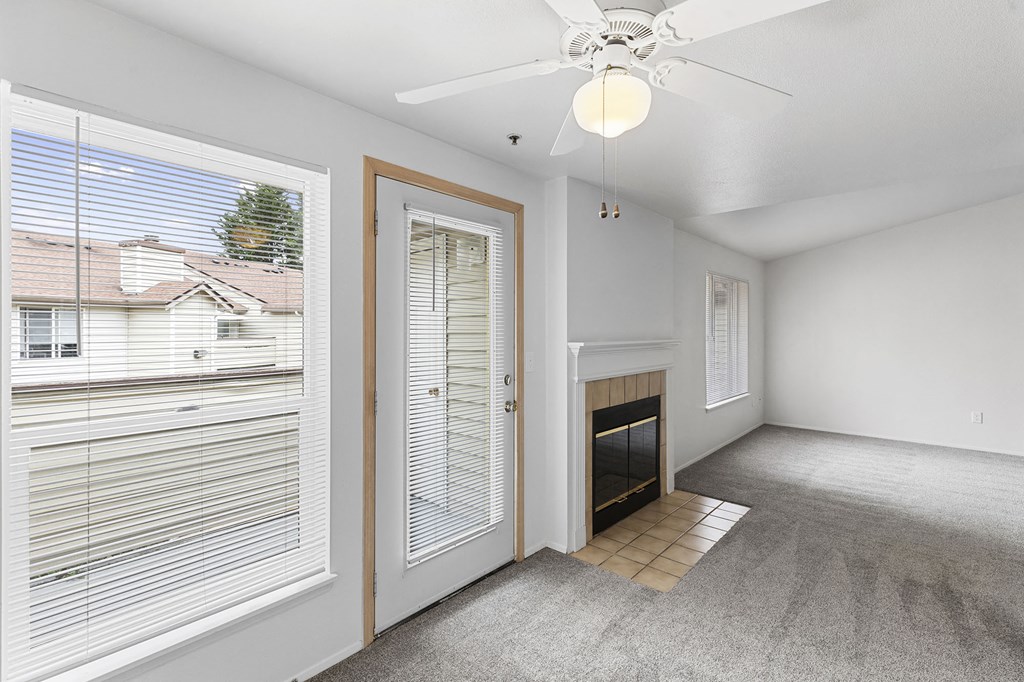 an empty living room with a window and a door to a fireplace