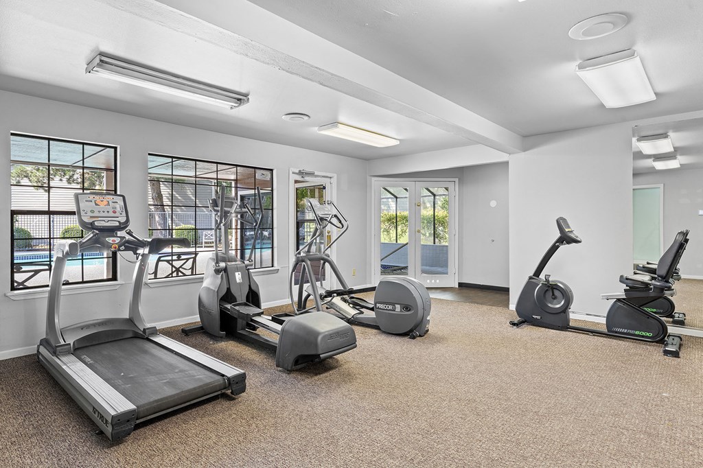 a gym with treadmills and other exercise equipment and windows