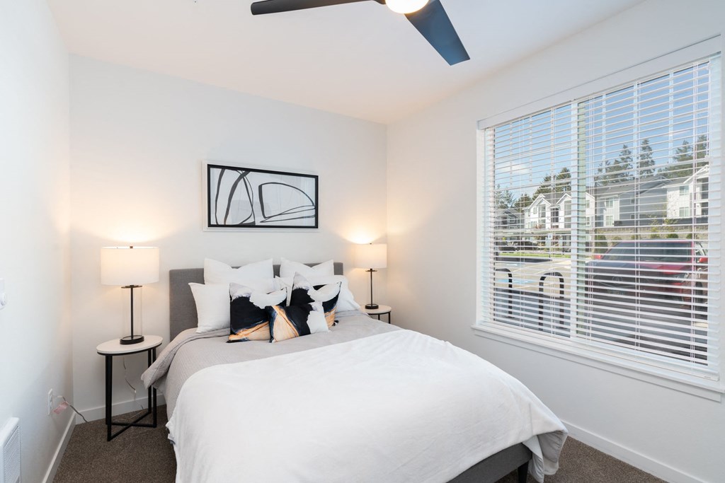 a bedroom with a large window and a white bed
