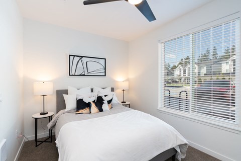 a bedroom with a large window and a white bed