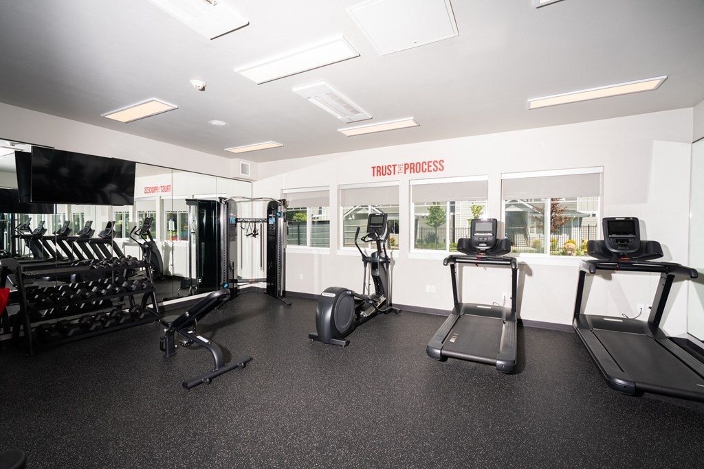 a gym with cardio equipment and weights on the floor