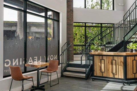 A wooden table with two chairs in front of a window with a view of a building outside.