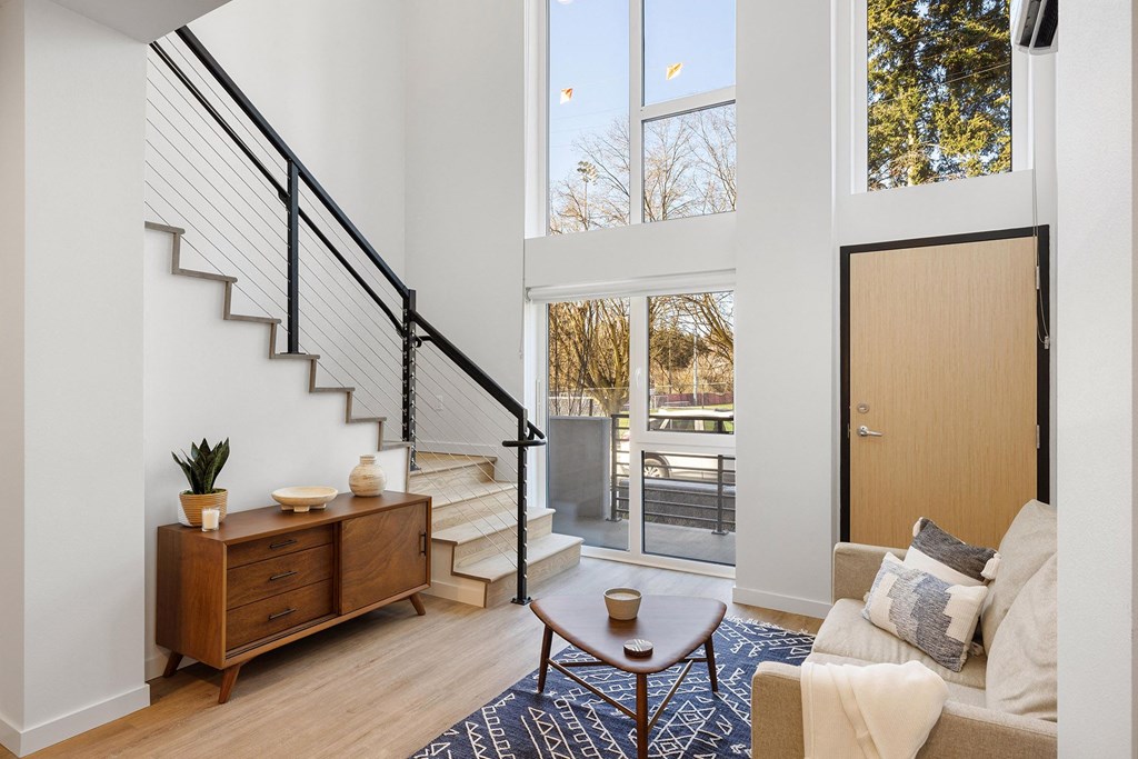 a living room with a staircase and a door to a balcony