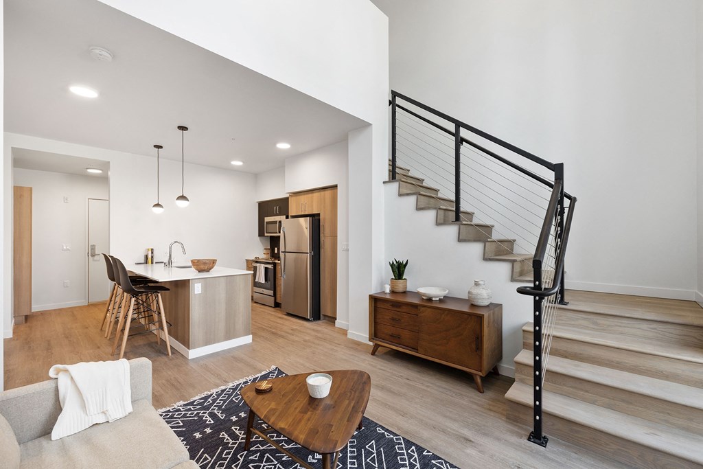 a living room with a staircase and a dining room and kitchen