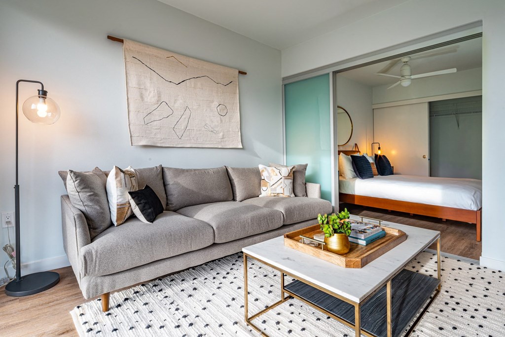 a living room with a couch and a coffee table and a bedroom with a bed