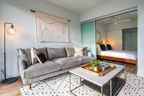 a living room with a couch and a coffee table and a bedroom with a bed