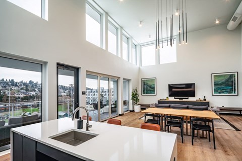 a kitchen with a sink and a table and a living room with windows