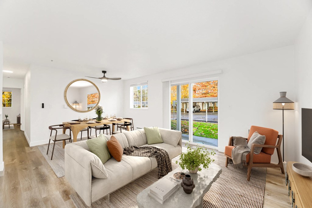 A living room with a white couch, a round mirror, and a ceiling fan.