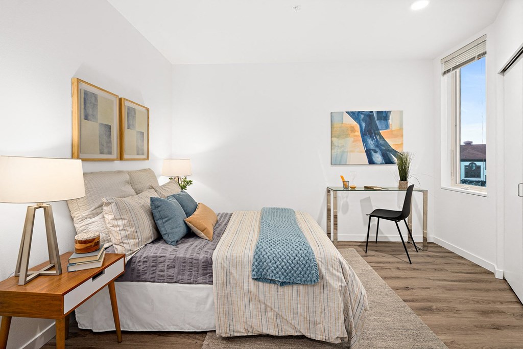 a bedroom with a bed and a desk and a window